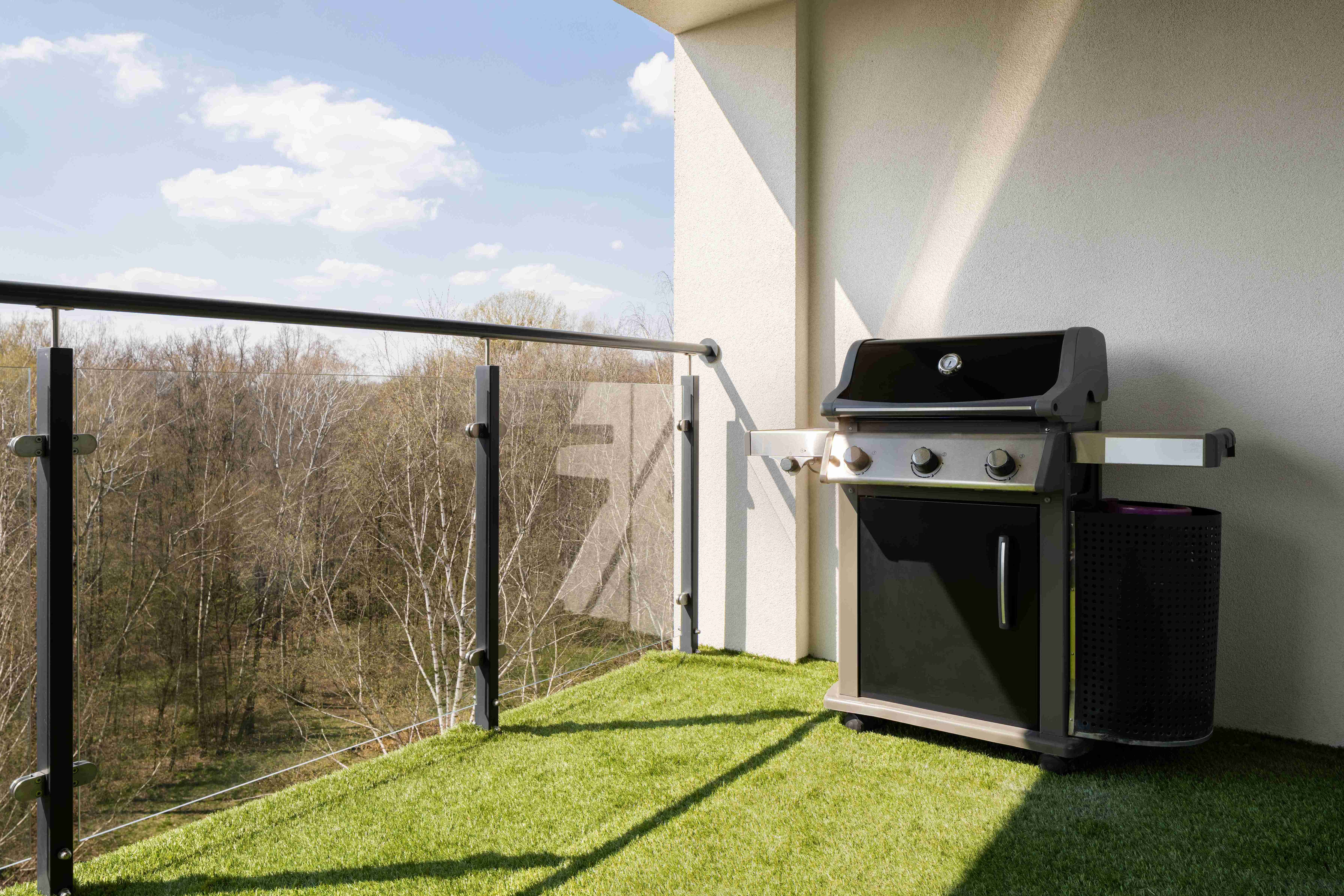 grill gazowy na balkonie wyłożonym sztuczną trawą