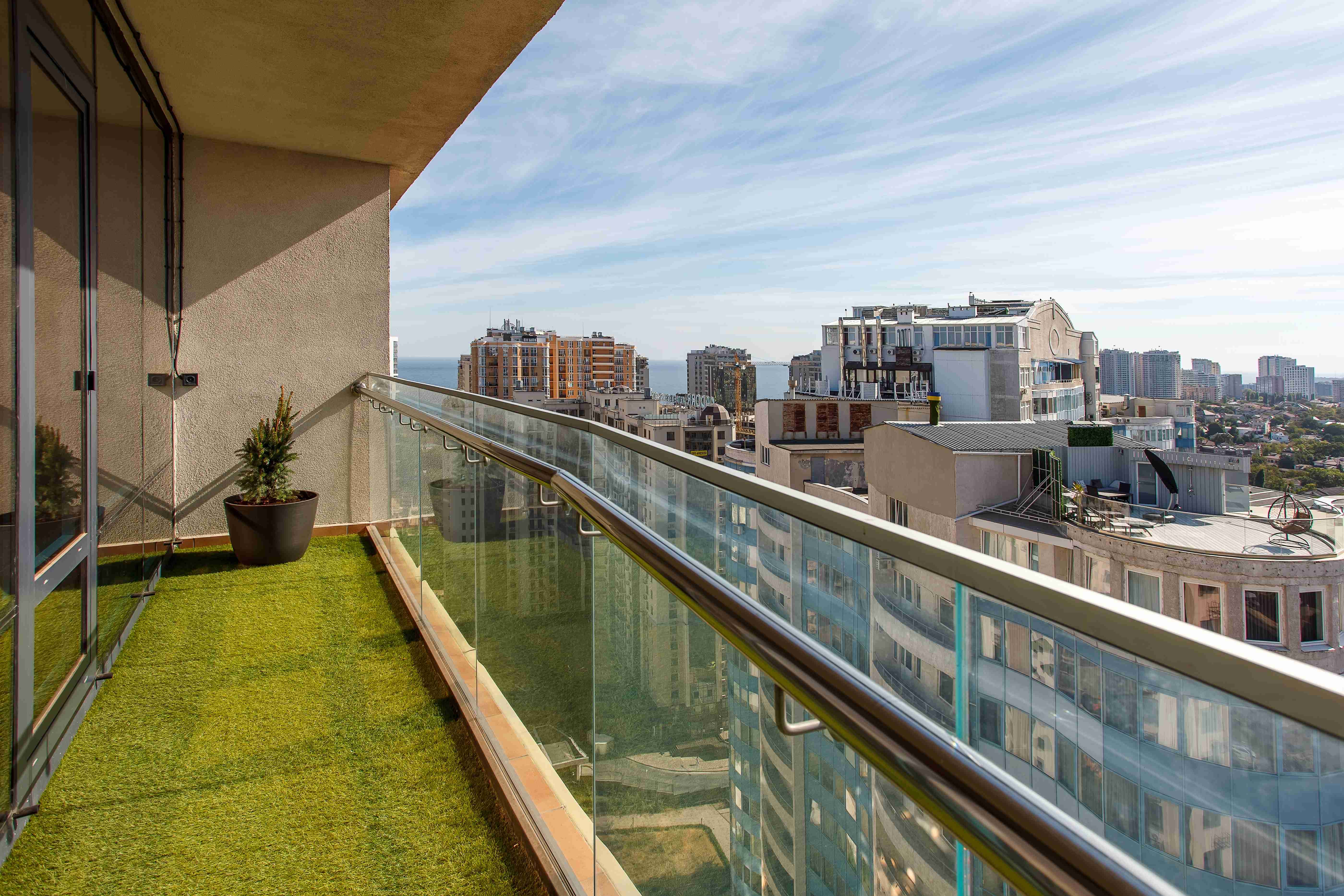 balkon ze szklaną balustradą wyłożony sztuczną trawą